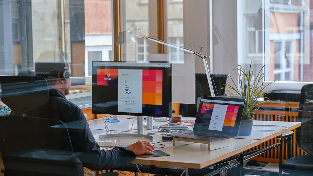 Blick in das Büro der Firma digitise, auf dem Schreibtisch stehen Monitore, auf denen ein Webseiten-Layout zu sehen ist.
