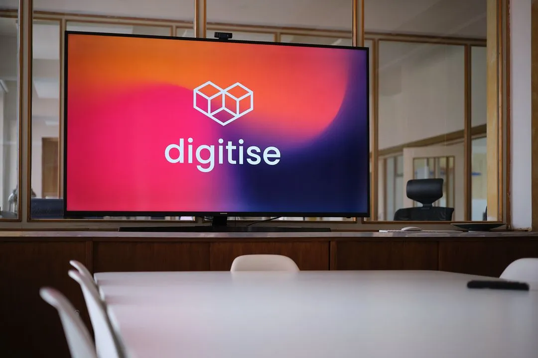 Monitor im Besprechungsraum, der das herzförmige Logo von digitise zeigt.